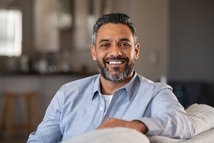 Portrait of happy mid adult man sitting on sofa at home.